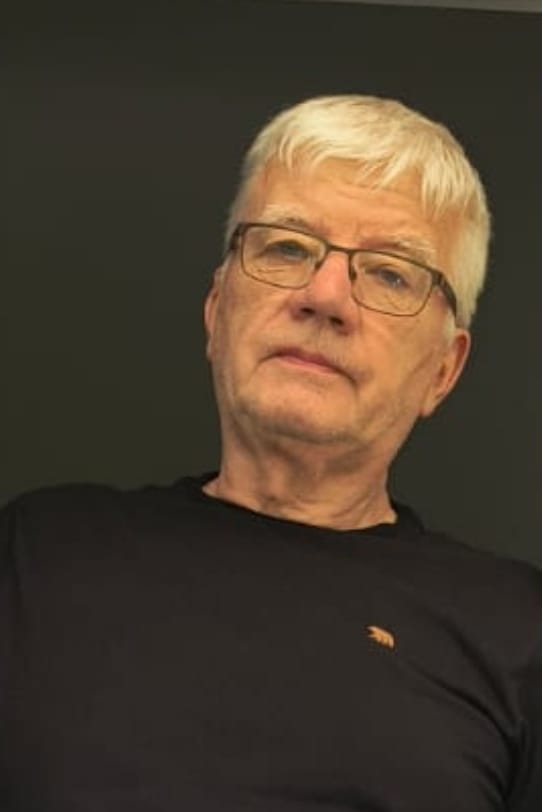 Retrato de Franz J. Brüseke, de óculos e cabelo branco, com camiseta preta